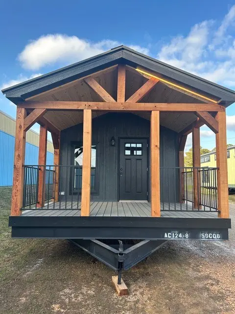 Front view of an AC-124 cabin with a gabled timber porch and dark siding