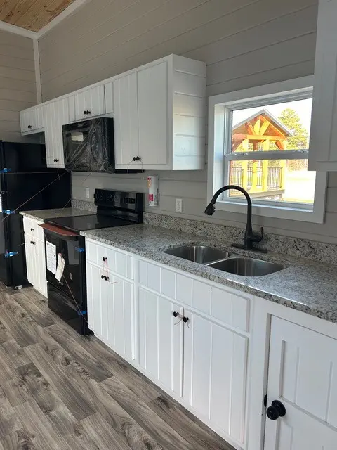 Kitchen with white cabinets, granite counters and a double sink