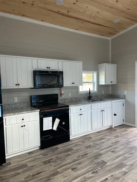 Kitchen with white cabinets, black appliances and a window over the sink