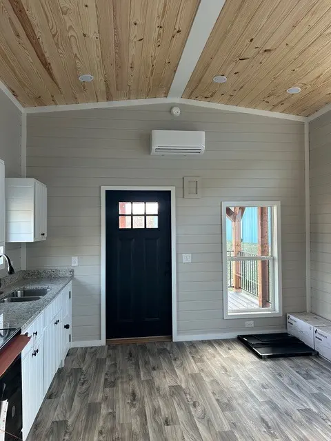 Interior with a black front door, mini split and gray shiplap walls