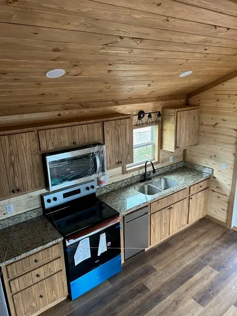 Kitchen with stainless appliances and granite counters under a pine ceiling