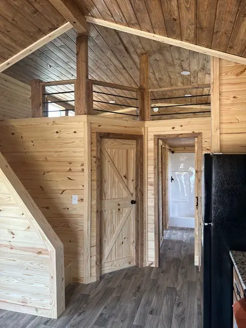 Interior with a loft, a pine door and a kitchen with black appliances